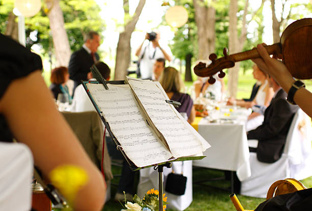 Violin players with sheet music at outdoor tent event
